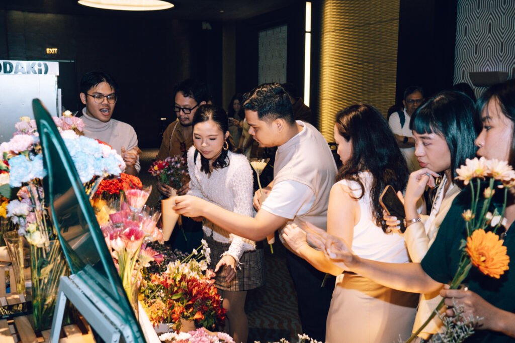 Group of people in a flower shop selecting colorful bouquets at a display counter.