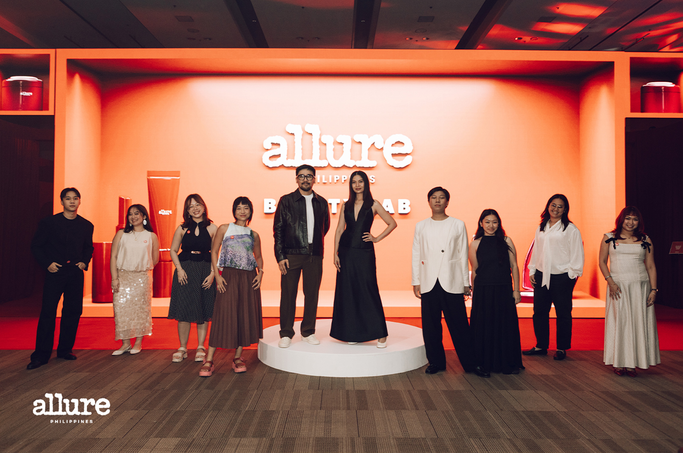 Group of models standing on a white circular podium on an orange Allure Philippines stage backdrop, posing for a fashion event photo.