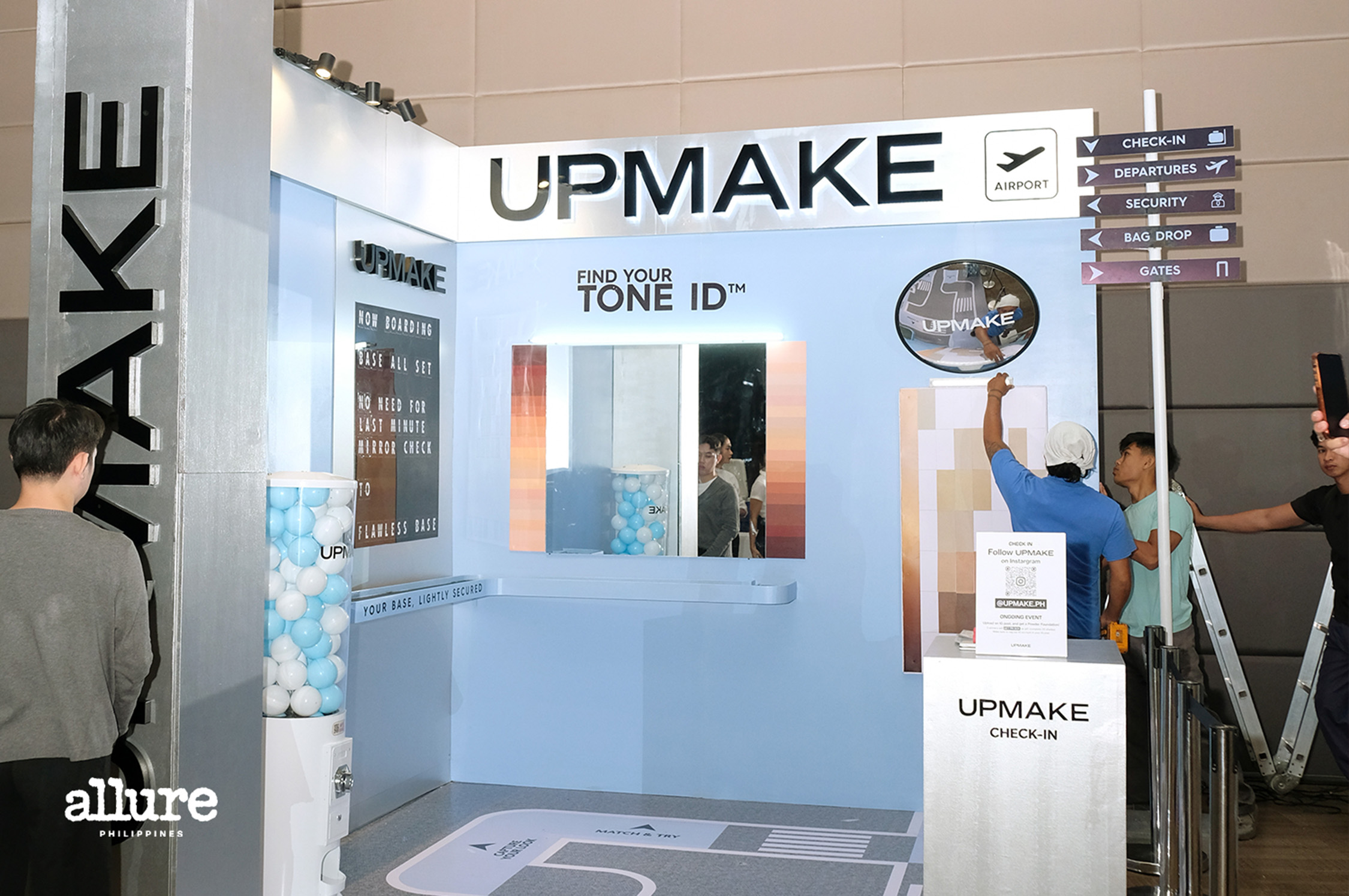 Exhibit booth for UPMAKE at an airport show with a large UPMAKE sign and blue display walls.