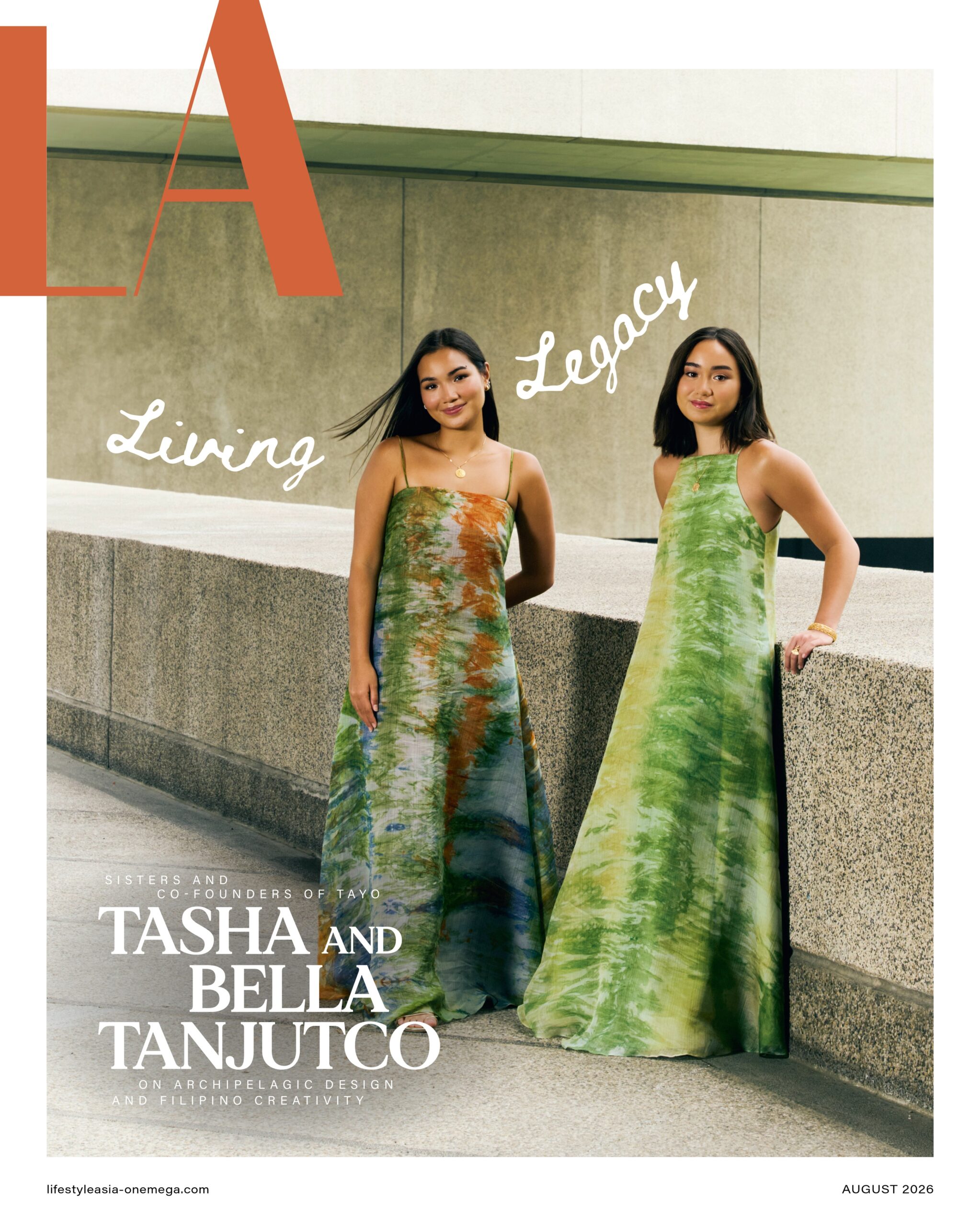 Two women in tie-dye dresses pose on a concrete ledge with bold orange letter A and cursive text overlay, a fashion magazine cover for August 2026.